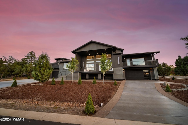 modern home featuring concrete driveway, a balcony, and an attached garage