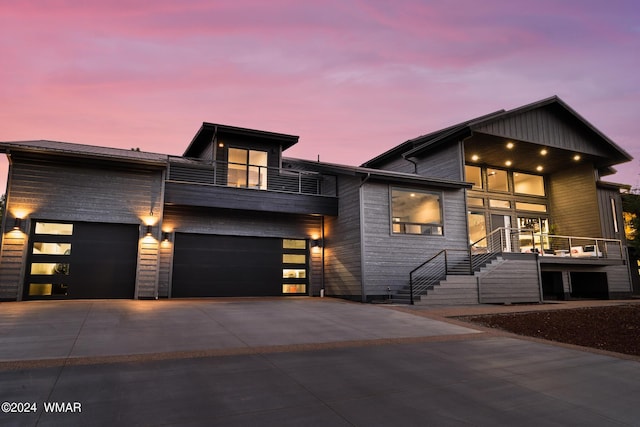 contemporary home with concrete driveway, a balcony, and an attached garage