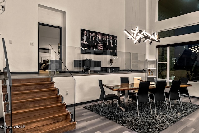 dining room with a chandelier, a high ceiling, stairway, and wood finished floors