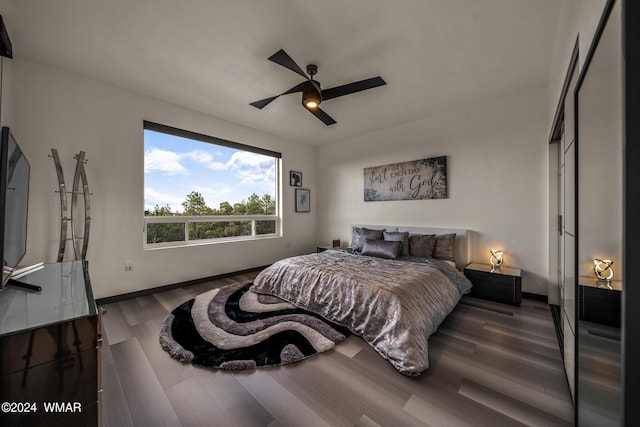 bedroom with dark wood finished floors, baseboards, and ceiling fan