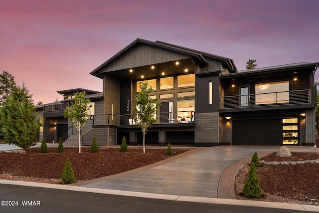 contemporary home with driveway, an attached garage, and a balcony