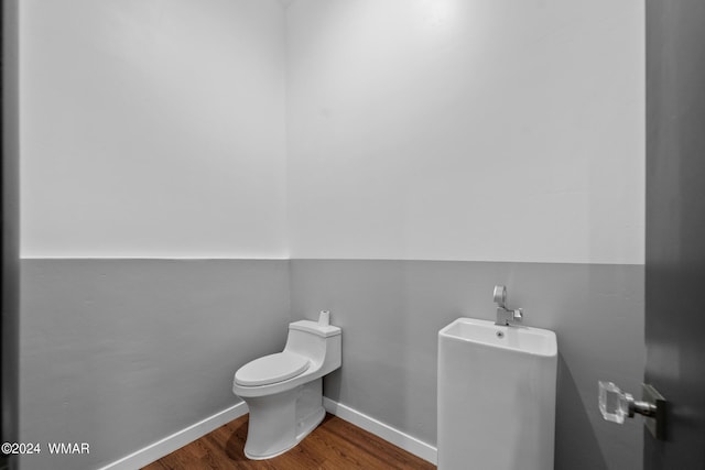 half bathroom featuring toilet, baseboards, and wood finished floors