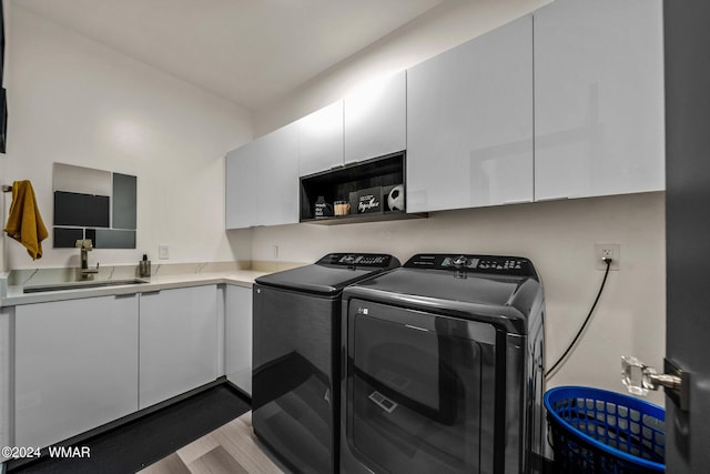 washroom featuring cabinet space, a sink, and washing machine and clothes dryer