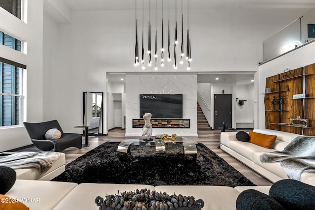 living area with a towering ceiling, light wood-style floors, and a high end fireplace