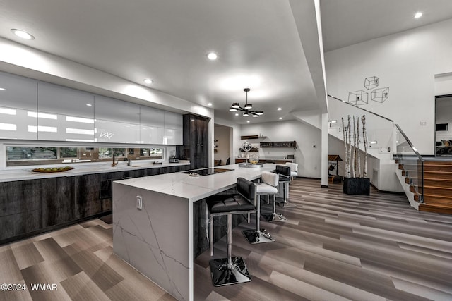 kitchen featuring a large island, modern cabinets, light stone counters, decorative light fixtures, and black electric cooktop