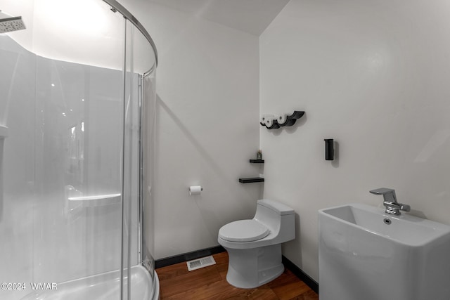 bathroom with visible vents, toilet, a stall shower, wood finished floors, and baseboards