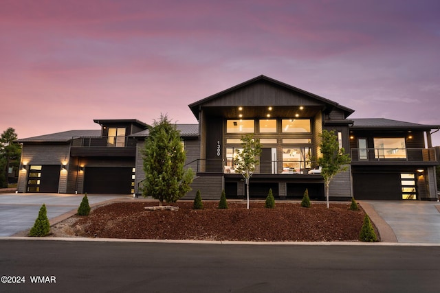 modern home featuring a balcony, an attached garage, and concrete driveway