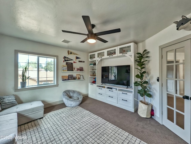 unfurnished living room with visible vents, baseboards, ceiling fan, and dark carpet