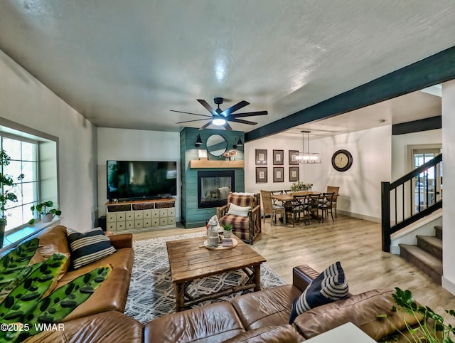 living room with stairway, plenty of natural light, a glass covered fireplace, and wood finished floors