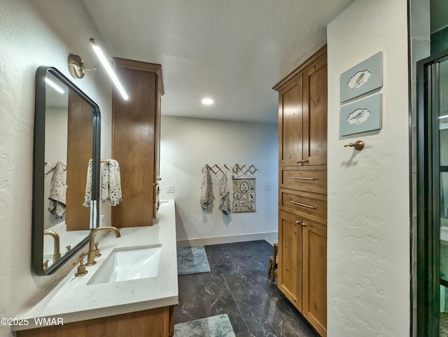 bathroom featuring recessed lighting, baseboards, vanity, and a textured wall