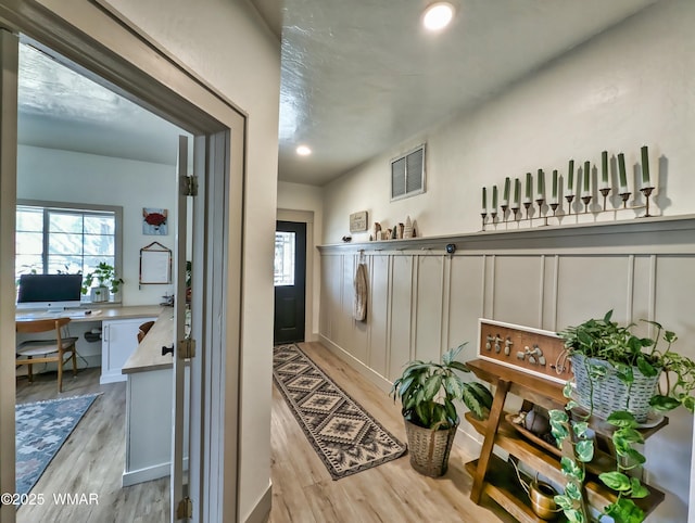 corridor with light wood-style flooring, recessed lighting, visible vents, and a wealth of natural light