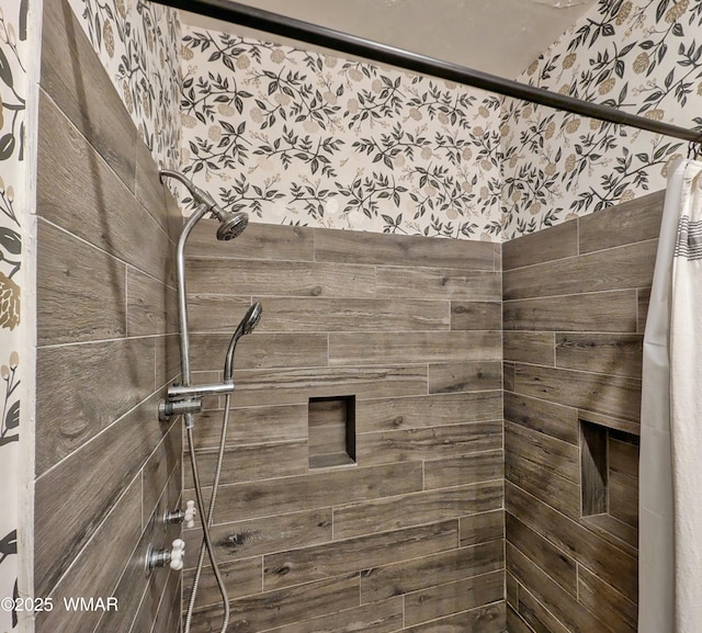 bathroom with a tile shower and wallpapered walls