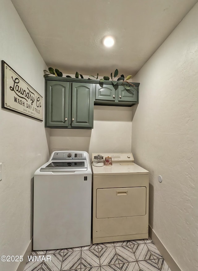 washroom featuring cabinet space, baseboards, and washer and clothes dryer