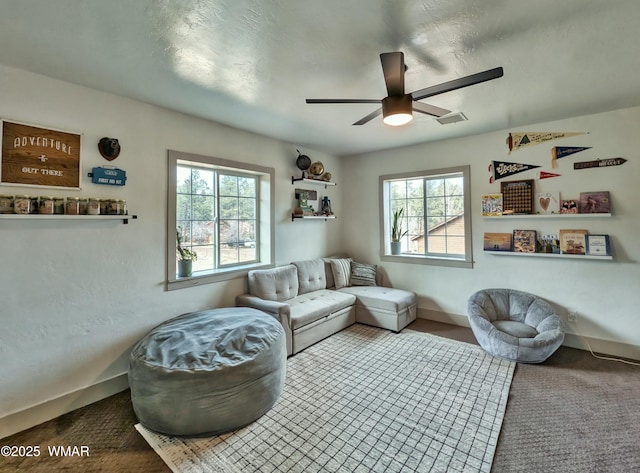 living area with visible vents, baseboards, carpet, and a ceiling fan