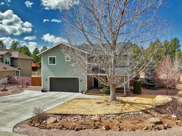 view of front of house featuring a garage, concrete driveway, covered porch, and fence