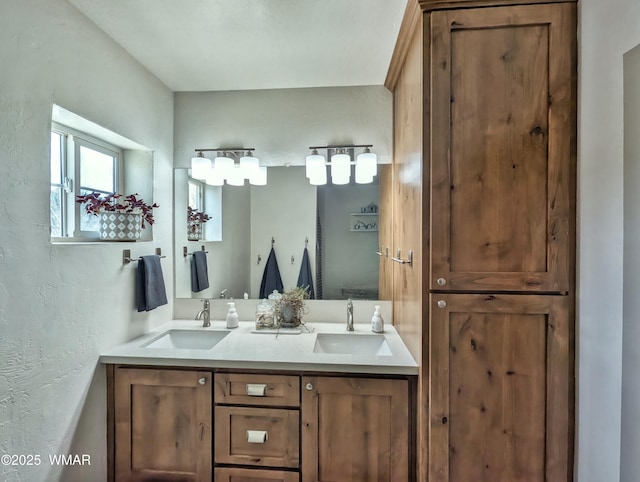 full bath with double vanity, a textured wall, and a sink