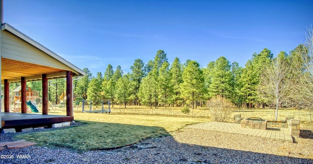 view of yard featuring a patio, an outdoor fire pit, playground community, and a trampoline