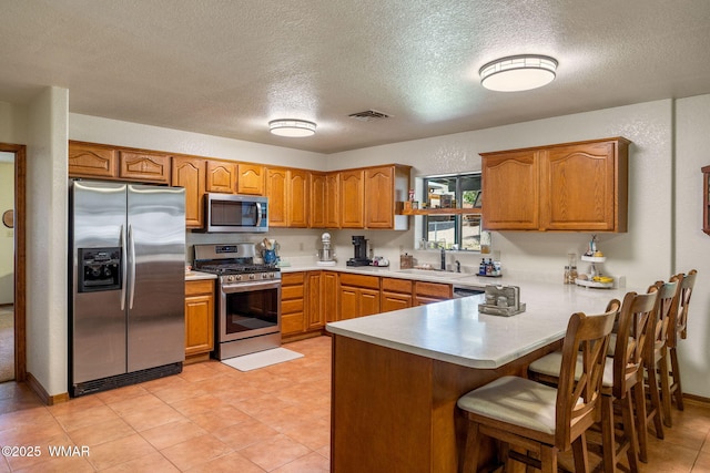 1030 Chamberlain Way, Show Low, AZ 85901 - kitchen with appliances with stainless steel finishes, a peninsula, brown cabinetry, a textured ceiling, and light countertops
