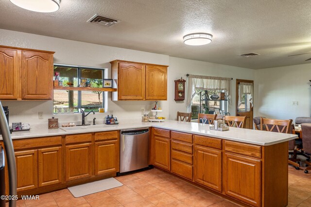 1030 Chamberlain Way, Show Low, AZ 85901 - kitchen featuring stainless steel dishwasher, a peninsula, light countertops, brown cabinets, and a textured ceiling