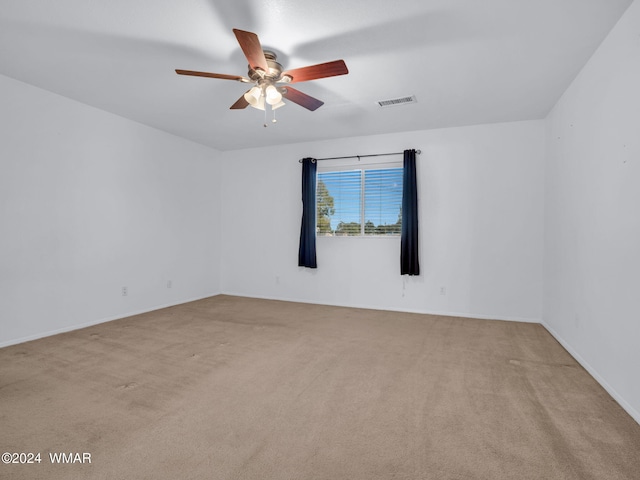 spare room with a ceiling fan, light colored carpet, and visible vents