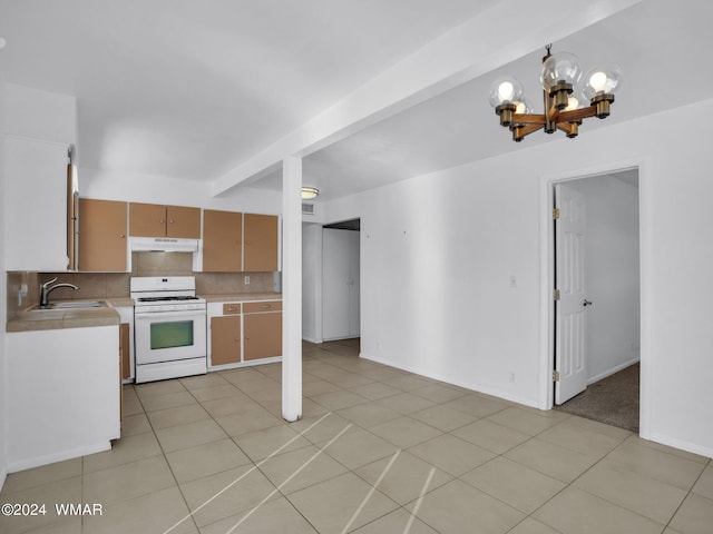 kitchen with under cabinet range hood, a sink, light countertops, decorative backsplash, and white gas range