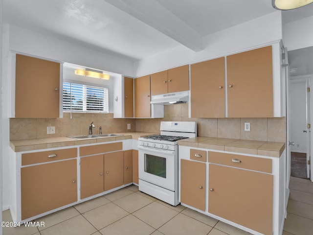 kitchen with tasteful backsplash, a sink, white gas stove, under cabinet range hood, and beam ceiling