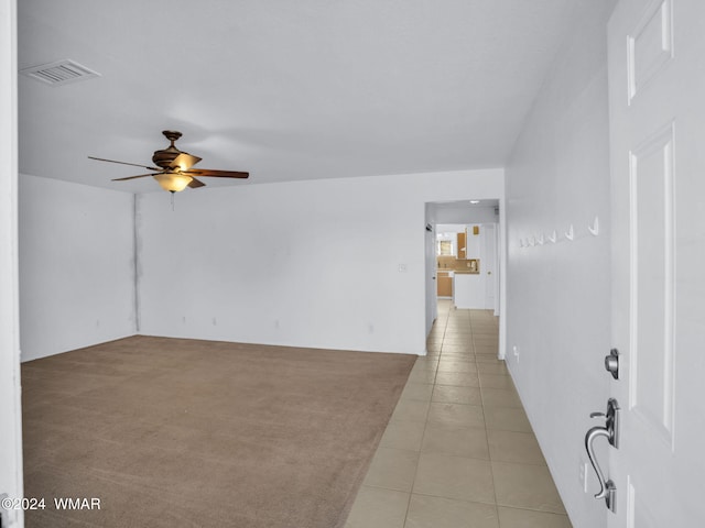 spare room with visible vents, ceiling fan, light carpet, and light tile patterned floors