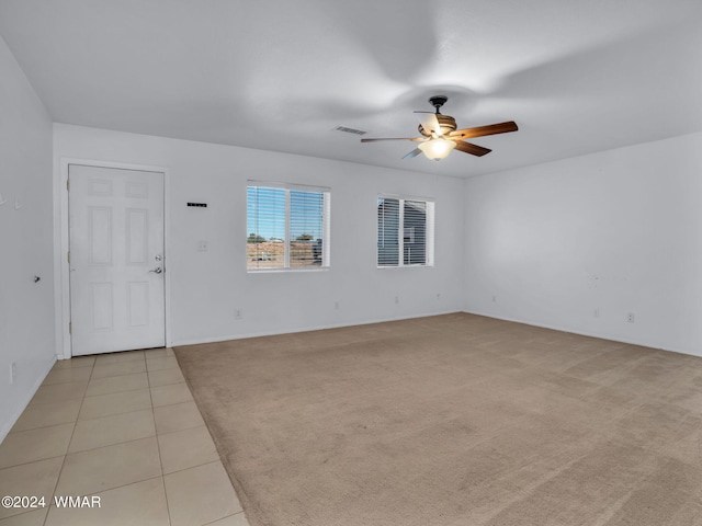 unfurnished room featuring a ceiling fan, light carpet, visible vents, and light tile patterned flooring