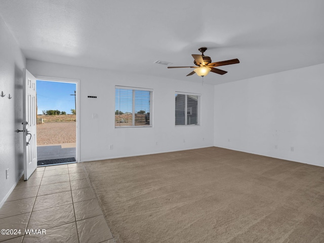 empty room with carpet, visible vents, and a ceiling fan