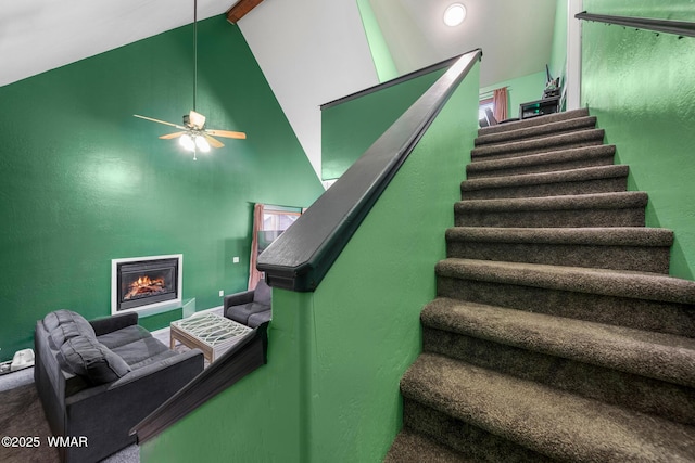242 E Pinecrest Dr, Pinetop, AZ 85935 - staircase featuring beamed ceiling, high vaulted ceiling, a glass covered fireplace, and ceiling fan