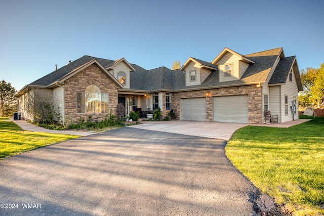 new england style home with a shingled roof, stone siding, aphalt driveway, an attached garage, and a front yard