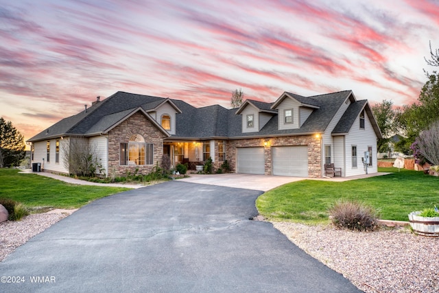 view of front of home with a garage, driveway, a front lawn, and stone siding