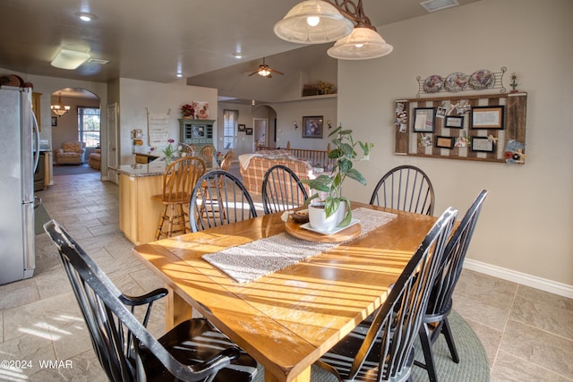 dining space featuring baseboards, visible vents, arched walkways, a ceiling fan, and vaulted ceiling