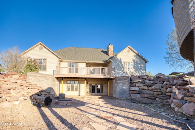 back of house featuring a patio, an outdoor fire pit, roof with shingles, a wooden deck, and a chimney