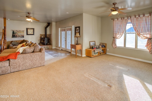 living room with ceiling fan, french doors, a wood stove, and baseboards