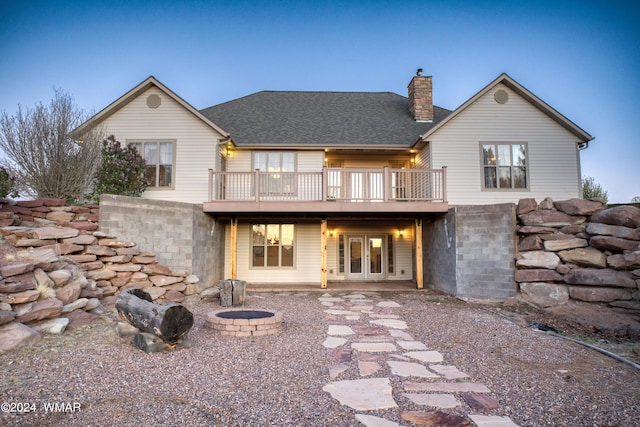 rear view of property featuring an outdoor fire pit, roof with shingles, a chimney, and a wooden deck