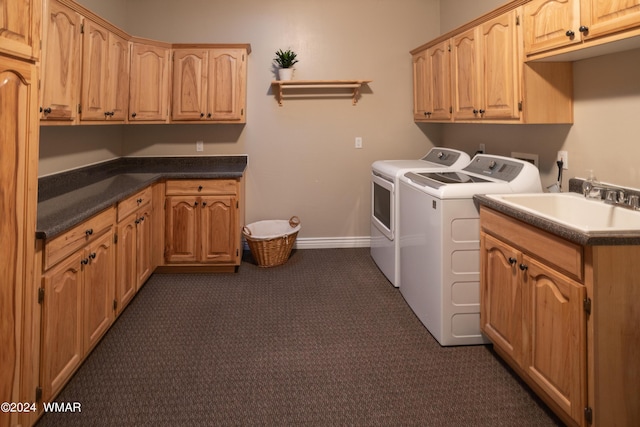 washroom featuring a sink, washing machine and clothes dryer, cabinet space, and baseboards