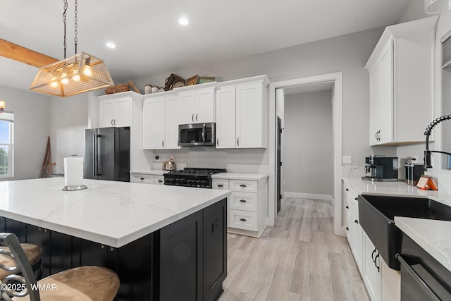 kitchen with high end refrigerator, stainless steel microwave, black range with gas cooktop, a center island, and a sink