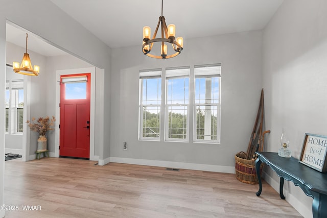 entryway with a chandelier, light wood-type flooring, and baseboards