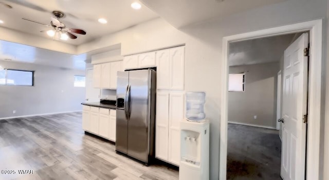 kitchen with dark countertops, stainless steel refrigerator with ice dispenser, light wood-style flooring, and white cabinets