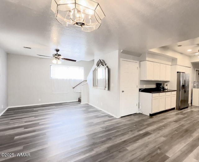 kitchen with ceiling fan with notable chandelier, stainless steel refrigerator with ice dispenser, wood finished floors, and open floor plan