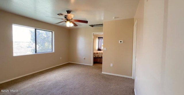 carpeted empty room with ceiling fan, visible vents, and baseboards