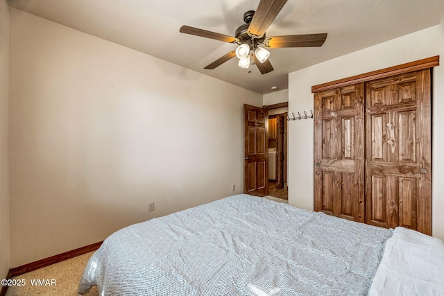 carpeted bedroom featuring a closet, baseboards, and a ceiling fan