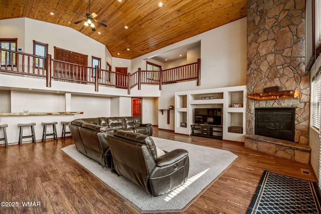 living area featuring a fireplace, a ceiling fan, high vaulted ceiling, wooden ceiling, and wood finished floors