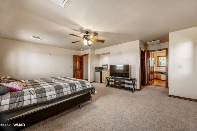 bedroom with baseboards, ensuite bathroom, a ceiling fan, visible vents, and light colored carpet