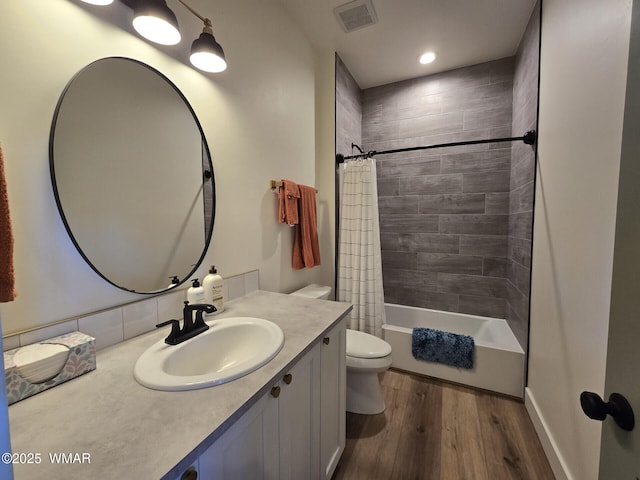 bathroom featuring visible vents, toilet, shower / bath combo, wood finished floors, and vanity