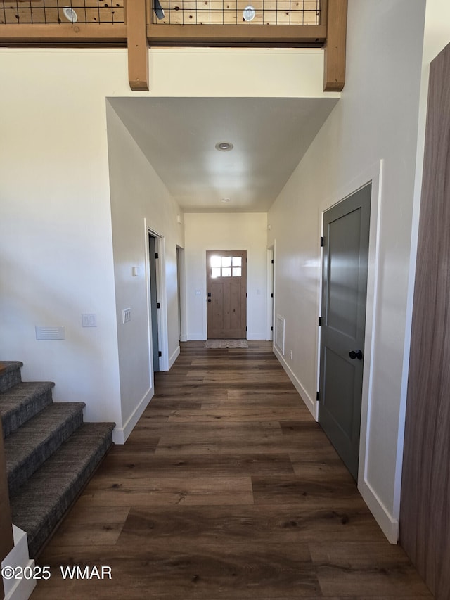 interior space with visible vents, dark wood-style floors, baseboards, a towering ceiling, and stairs