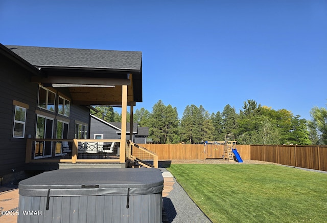 view of yard with a playground, a fenced backyard, and a hot tub