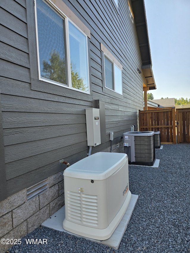 view of side of home with central AC unit and fence