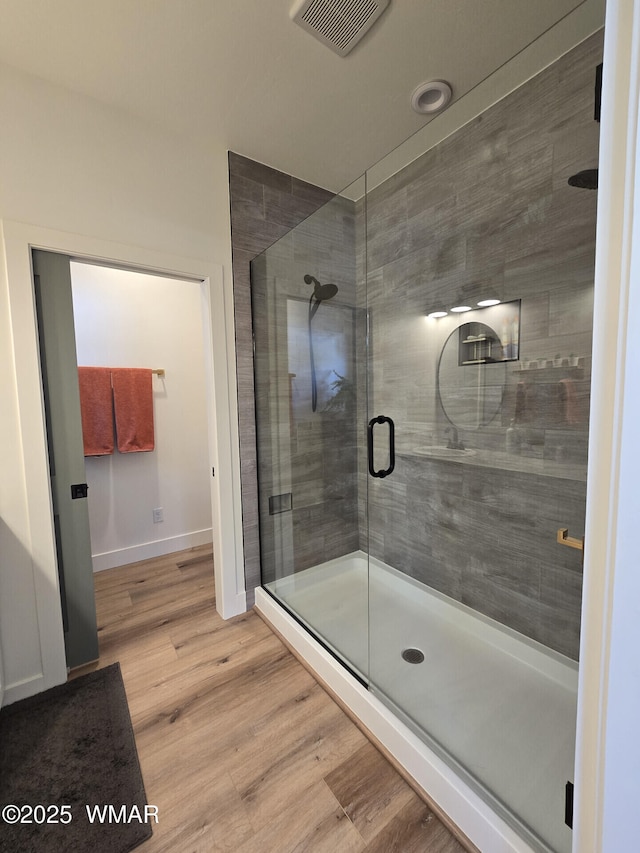 full bathroom featuring visible vents, baseboards, wood finished floors, and a shower stall